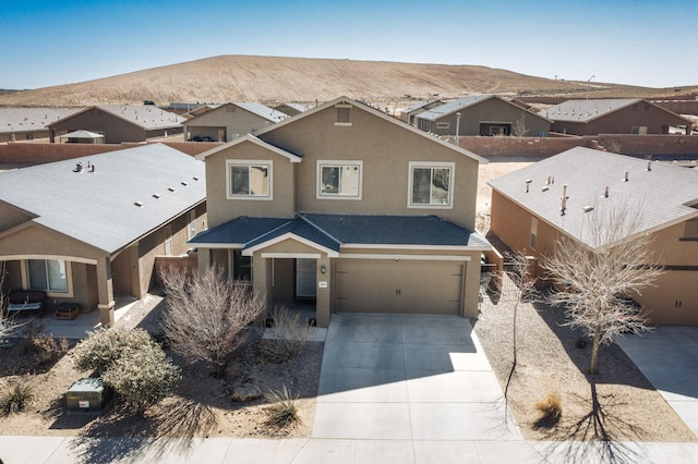 view of front of house with driveway, an attached garage, fence, a mountain view, and stucco siding