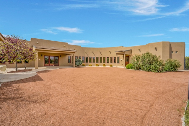 rear view of property featuring stucco siding and french doors