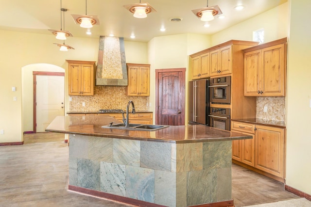 kitchen with visible vents, a kitchen island with sink, a sink, custom exhaust hood, and high end refrigerator