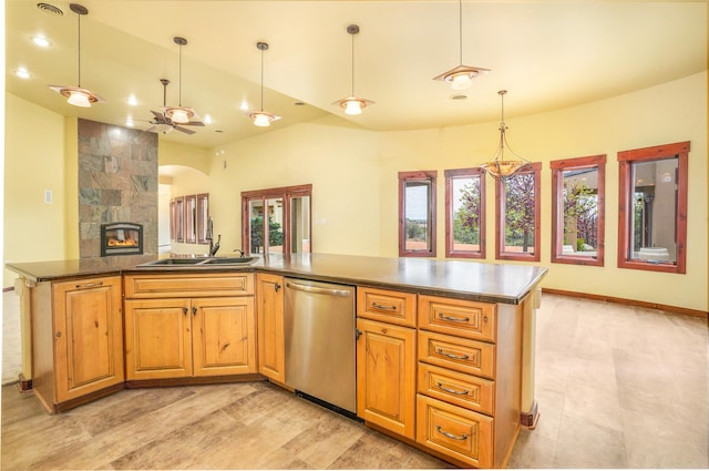 kitchen featuring a ceiling fan, a tiled fireplace, a sink, stainless steel dishwasher, and open floor plan