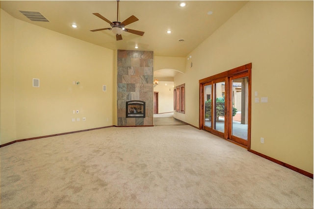 unfurnished living room with a ceiling fan, baseboards, visible vents, carpet floors, and arched walkways