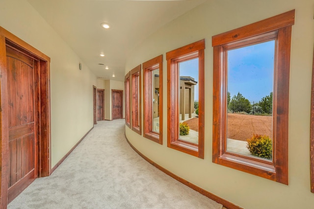 hallway with recessed lighting, light colored carpet, and baseboards