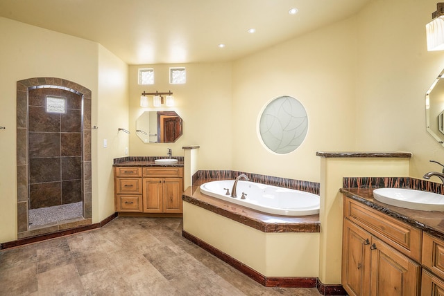 bathroom featuring a bath, tiled shower, two vanities, and a sink