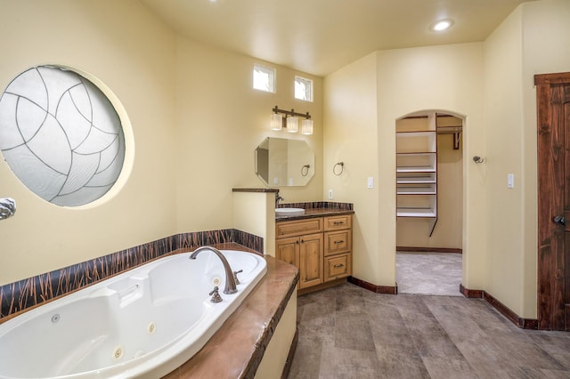 bathroom with recessed lighting, vanity, baseboards, and a whirlpool tub