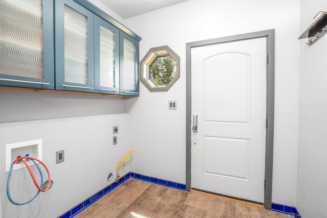 laundry room featuring gas dryer hookup, hookup for a washing machine, wood finished floors, cabinet space, and electric dryer hookup