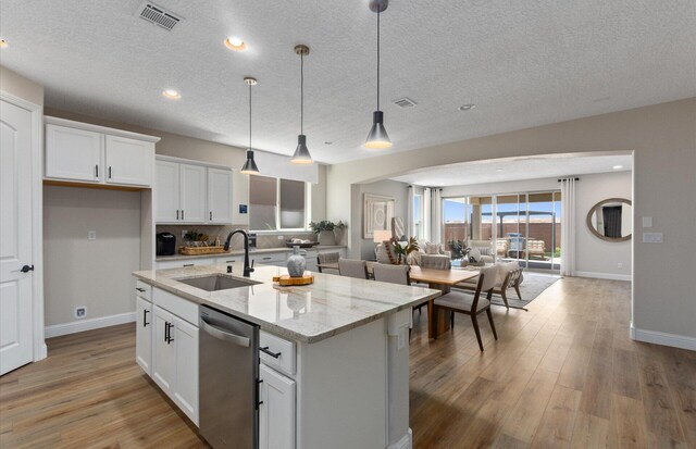 938 Lazuli Rd SE, Rio Rancho, NM 87124 - kitchen with visible vents, white cabinetry, a sink, stainless steel dishwasher, and open floor plan
