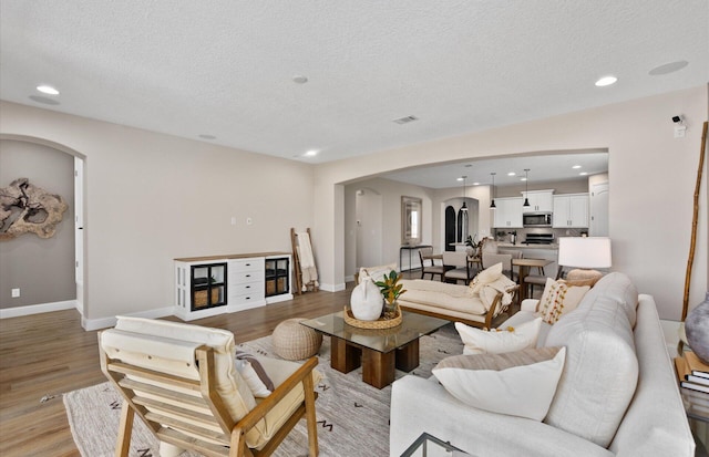 938 Lazuli Rd SE, Rio Rancho, NM 87124 - living room featuring baseboards, light wood-type flooring, recessed lighting, arched walkways, and a textured ceiling