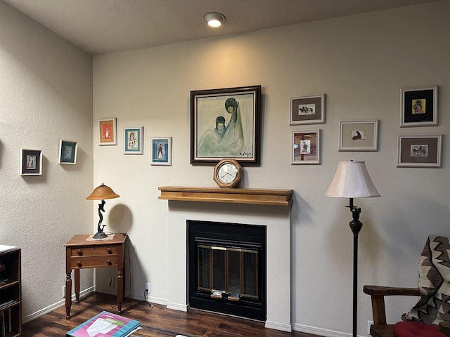 living room featuring a glass covered fireplace, baseboards, and wood finished floors