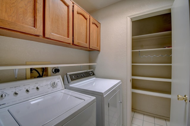 laundry area with cabinet space, light tile patterned floors, a textured wall, and independent washer and dryer