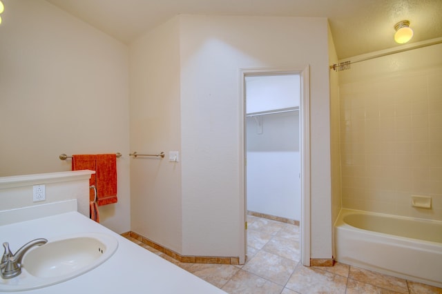 full bathroom with shower / tub combination, tile patterned flooring, a sink, baseboards, and a walk in closet