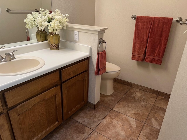 bathroom with toilet, tile patterned flooring, baseboards, and vanity