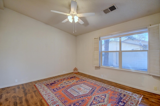 spare room featuring a ceiling fan, wood finished floors, visible vents, and baseboards