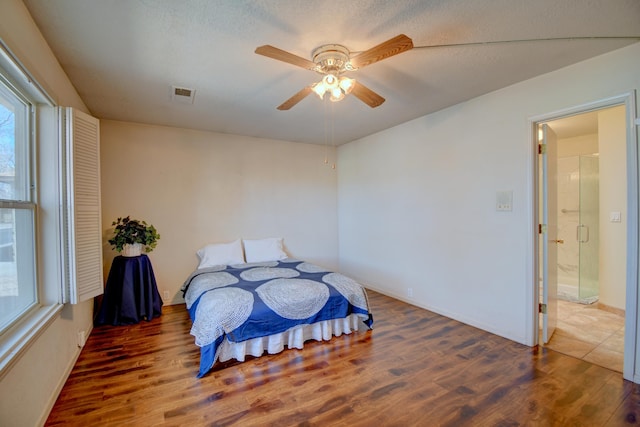 bedroom with a ceiling fan, a textured ceiling, visible vents, and wood finished floors