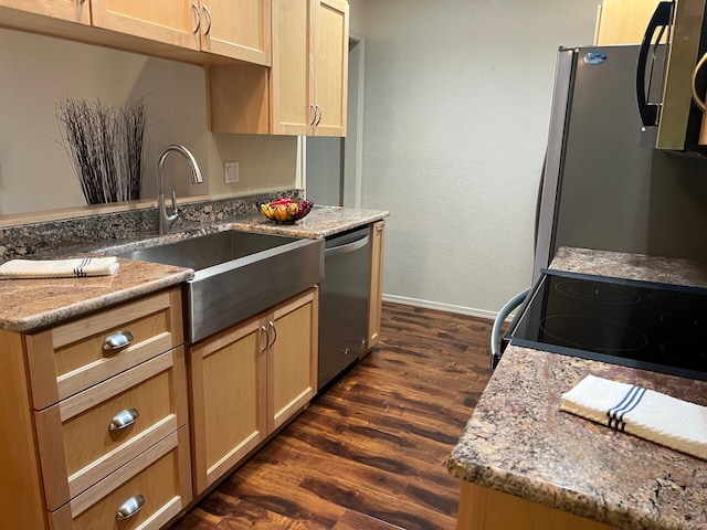 kitchen with stainless steel appliances, dark wood-type flooring, a sink, baseboards, and light stone countertops