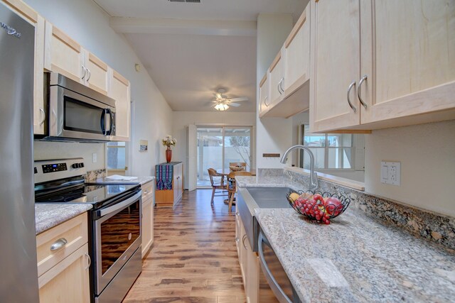 kitchen featuring light wood-style flooring, light brown cabinets, appliances with stainless steel finishes, and beamed ceiling