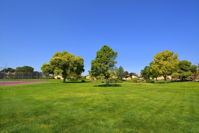 view of sport court with community basketball court, a community pool, fence, and a yard