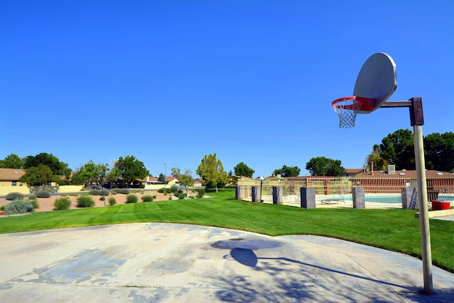 view of sport court with community basketball court, a community pool, fence, and a yard