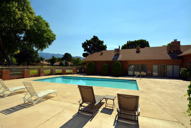 community pool featuring a mountain view, a patio, and fence