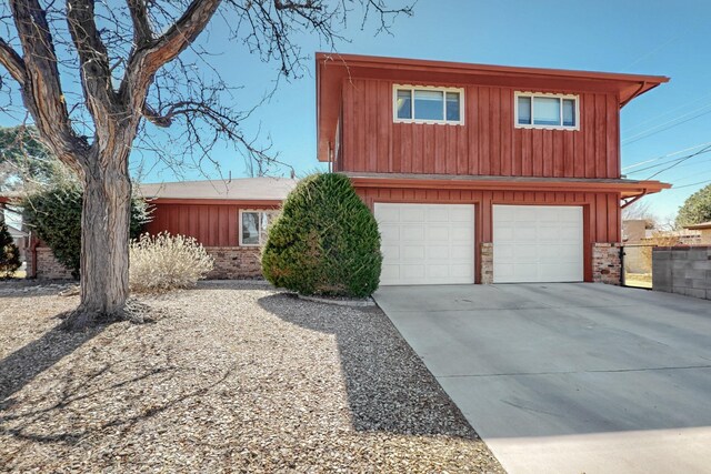 view of front of home featuring driveway, brick siding, board and batten siding, and an attached garage