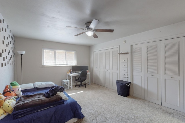 carpeted bedroom with a ceiling fan and two closets