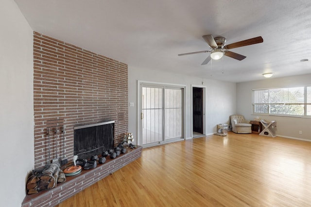 unfurnished living room with ceiling fan, a fireplace, wood finished floors, and baseboards