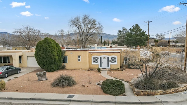 view of front of property featuring a garage, a mountain view, stucco siding, and concrete driveway
