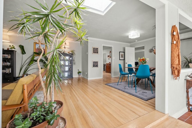 dining space with ornamental molding, a skylight, wood finished floors, and baseboards