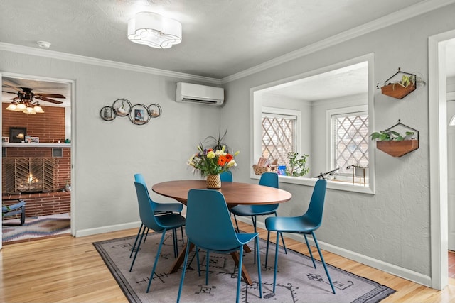 dining space featuring light wood-style flooring, a fireplace, ornamental molding, and a wall mounted AC