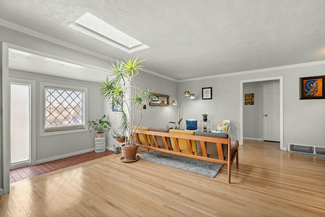 entryway with visible vents, ornamental molding, wood finished floors, baseboards, and a skylight