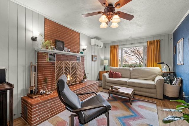 living area with a ceiling fan, a textured ceiling, ornamental molding, and wood finished floors