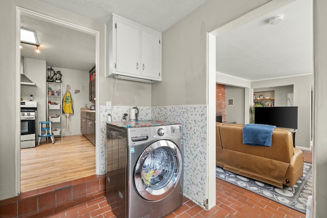 clothes washing area with washer / clothes dryer and brick floor