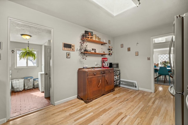bar with light wood-style floors, baseboards, freestanding refrigerator, and a wealth of natural light