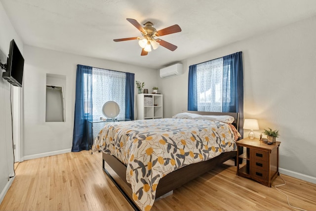 bedroom featuring an AC wall unit, light wood-style flooring, baseboards, and ceiling fan