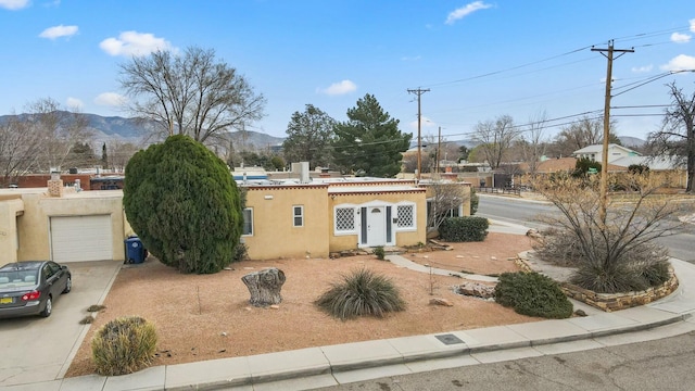 view of front of property featuring a mountain view, stucco siding, a chimney, and concrete driveway
