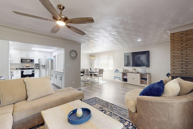 living room featuring baseboards, a textured ceiling, a ceiling fan, and light wood-style floors