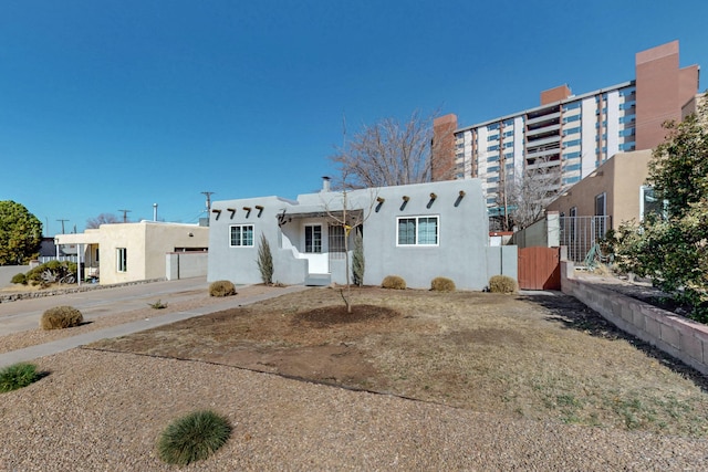 view of front facade with fence and stucco siding