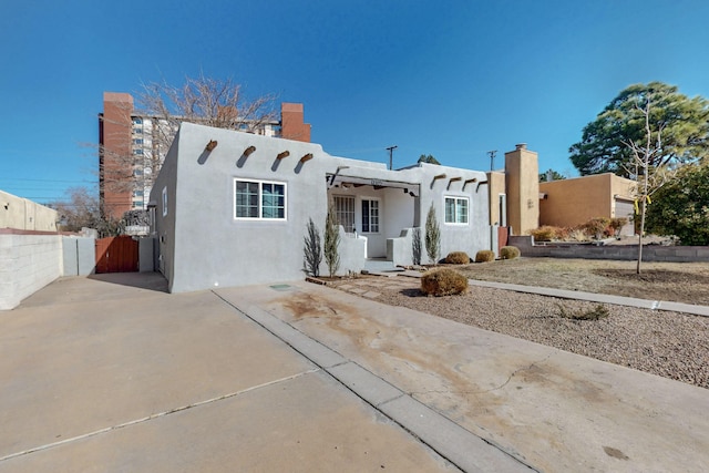 pueblo-style house featuring fence and stucco siding