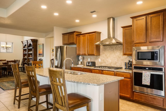 2721 Redondo Santa Fe Loop NE, Rio Rancho, NM 87144 - kitchen with a sink, brown cabinets, stainless steel appliances, wall chimney exhaust hood, and an island with sink