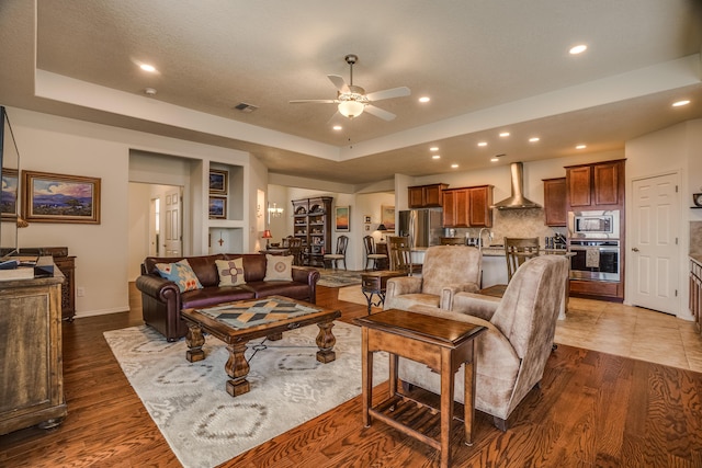 living area with visible vents, ceiling fan, recessed lighting, wood finished floors, and a raised ceiling