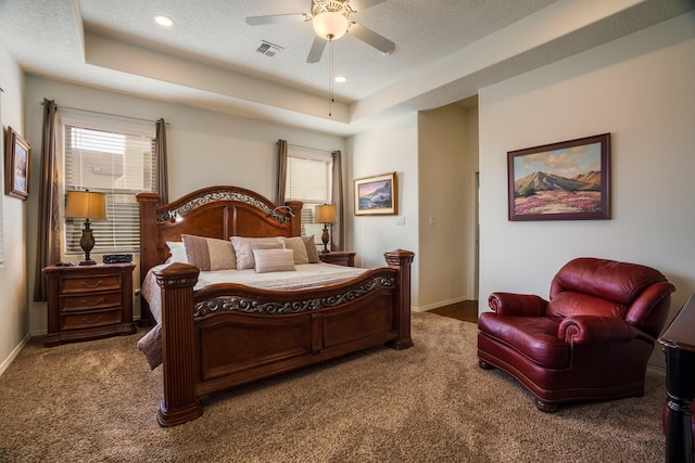 bedroom with a tray ceiling, visible vents, and multiple windows