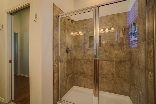 full bath with a shower stall, wood finished floors, and baseboards