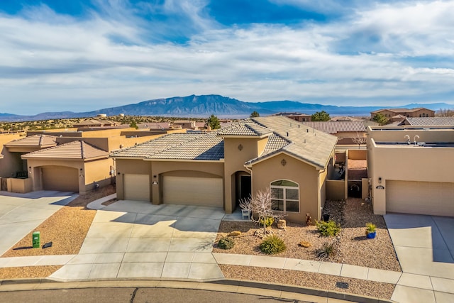 view of front of house featuring driveway, stucco siding, a garage, a tile roof, and a mountain view