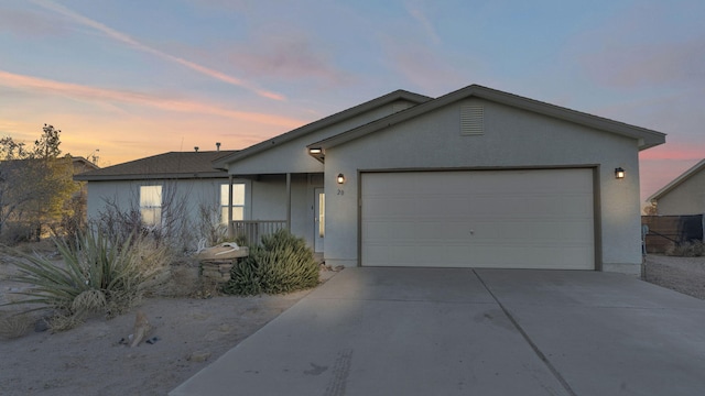 single story home with concrete driveway, an attached garage, and stucco siding