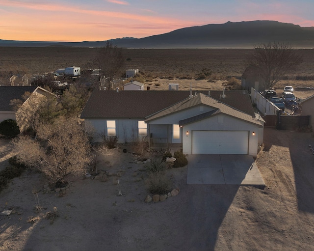 single story home with stucco siding, concrete driveway, a mountain view, fence, and a garage