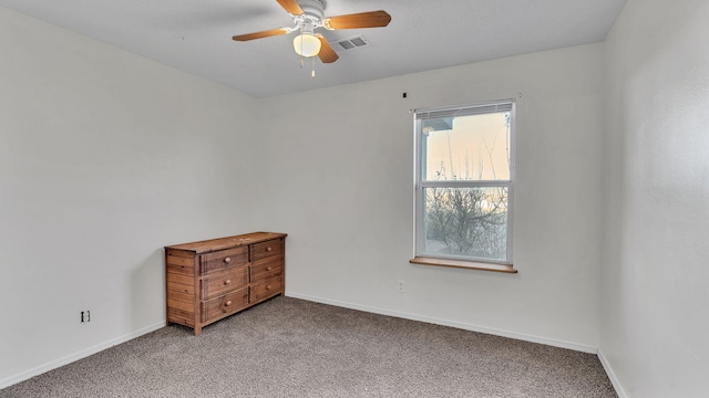 carpeted spare room with baseboards, visible vents, and a ceiling fan