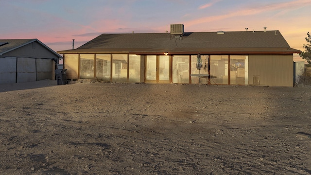 back of house at dusk featuring a sunroom