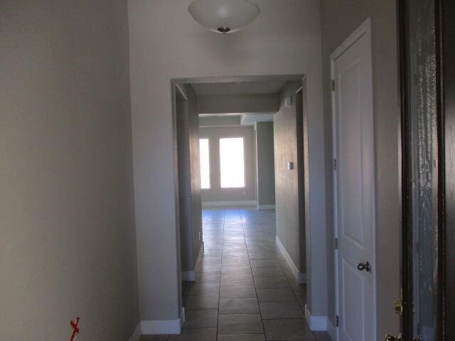 hallway with baseboards and tile patterned floors