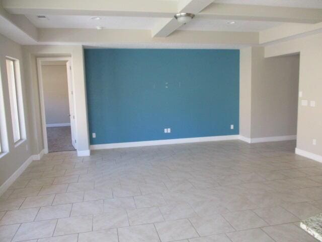 empty room with beam ceiling and baseboards