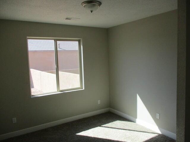 carpeted empty room with a textured ceiling and baseboards