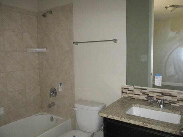 full bathroom featuring toilet,  shower combination, backsplash, and vanity